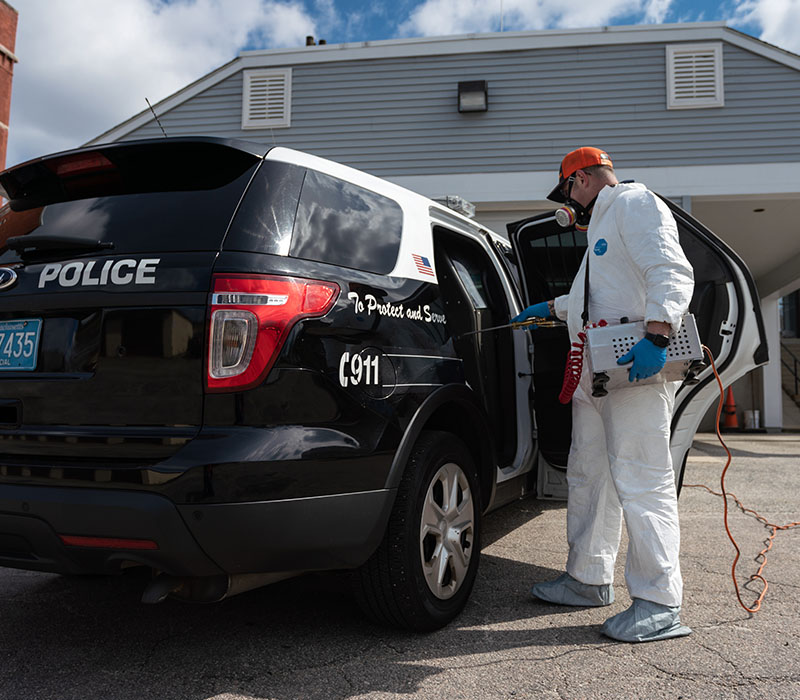 Catseye technician disinfecting a police cruiser with sprayer for Catseye's Viral-Guard service and remove contaminants